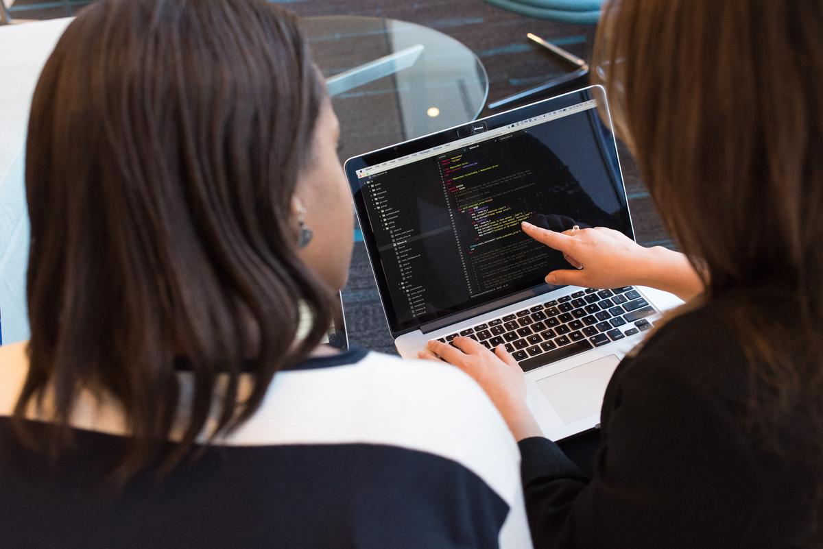 Two professionals discussing c vs c++ on a laptop.